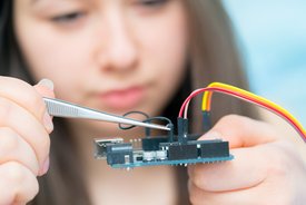 Student girl in electronics laboratory, experiment with microcontroller and robot cnc module