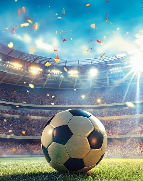 Ein Fußball liegt auf dem Rasen eines Stadions, umgeben von jubelnden Fans und festlich bunten Konfetti.